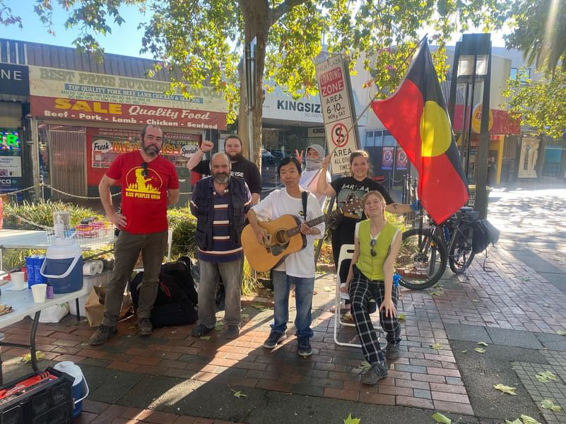 Image shows the community kitchen crew set up to serve some delicious meals with musical instruments and Aboriginal flags.