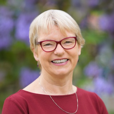 Janet Rice short blonde hair glasses dark red top