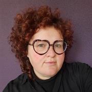 Dr Sophie Hindes brown curly hair large dark rimmed glasses