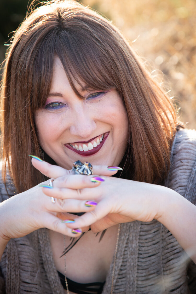 picutre of woman with brown hair, chin leaning on hands with fingers interloked