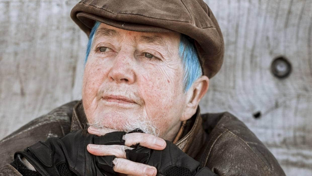 photo of Mani Bruce Mitchell thoughtful gaze wearing brown peaked cap