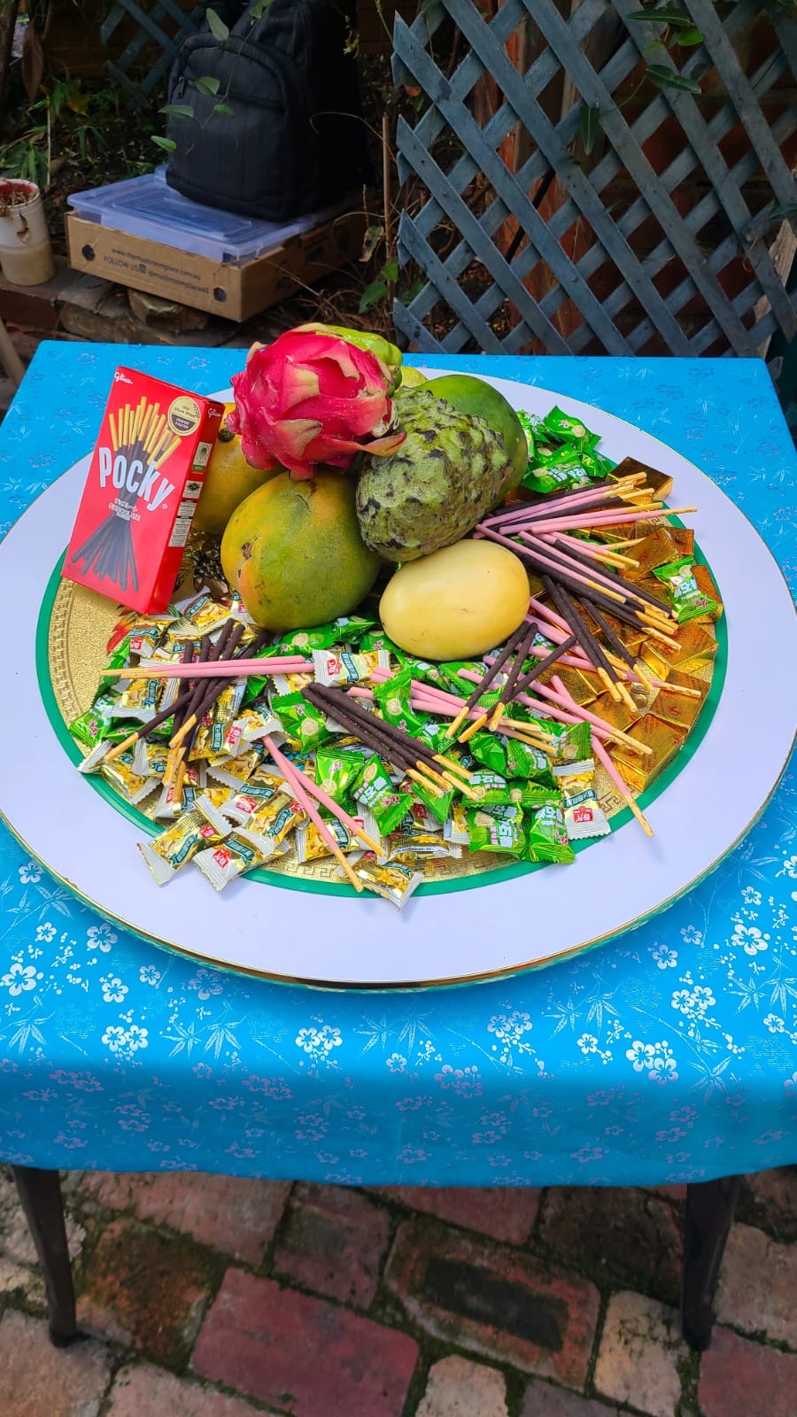 A large plate offering pocky biscuits, mango, dragon fruit, soursop and lollies 