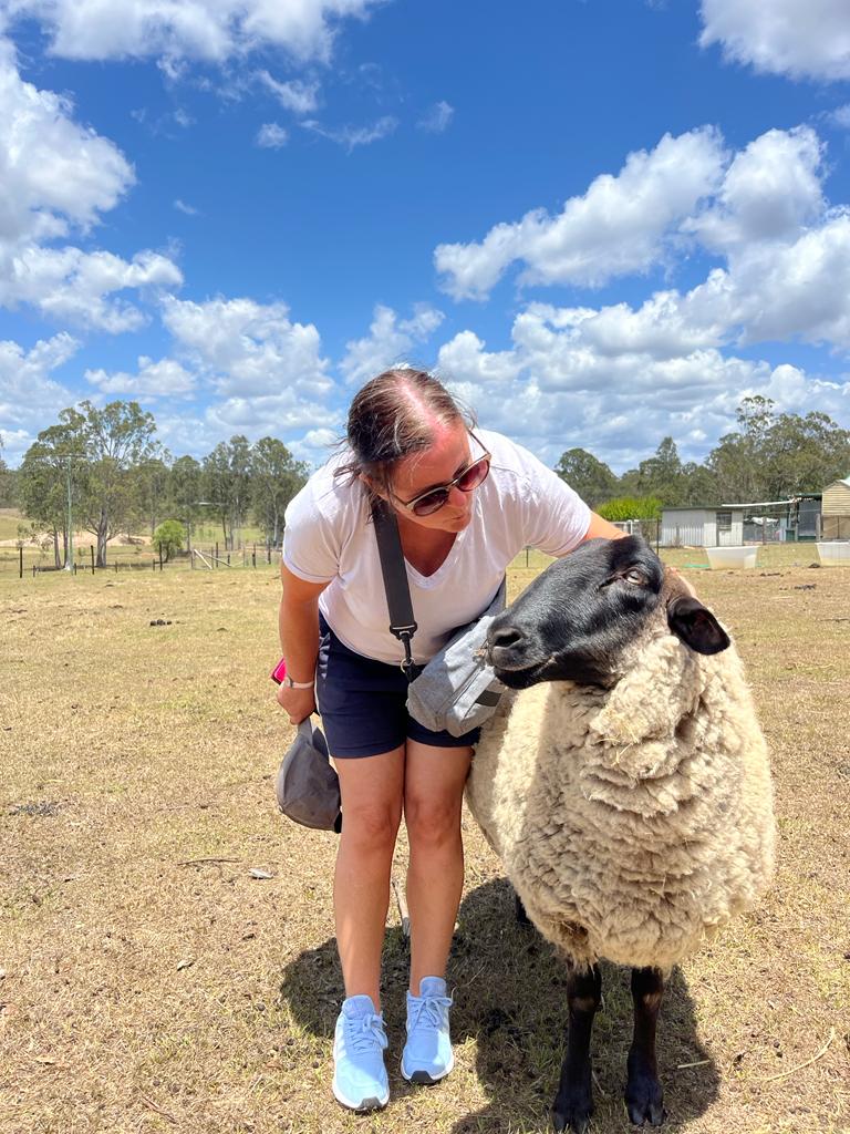 Rachel standing next to a sheep in a paddock