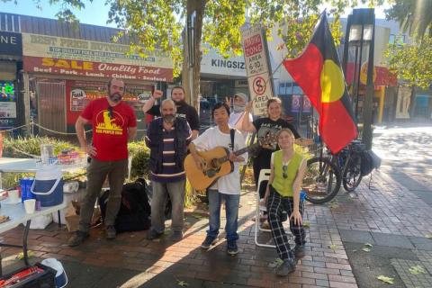 Image shows the community kitchen crew set up to serve some delicious meals with musical instruments and Aboriginal flags.