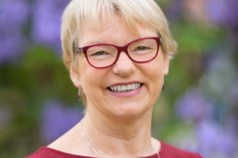 Janet Rice short blonde hair glasses dark red top