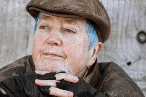 photo of Mani Bruce Mitchell thoughtful gaze wearing brown peaked cap