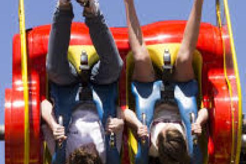 A couple of people hang upside down in a show ride