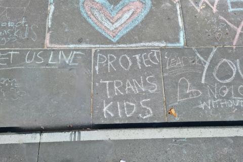 chalk of text 'protect trans kids' below a blue and pink heart