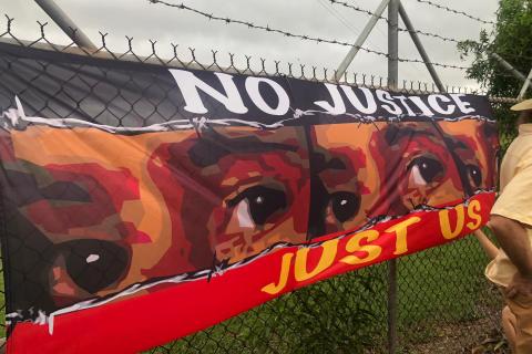 Image of a banner featuring eyes of young people locked up in prison. Text on banner reads 'no justice, just us'