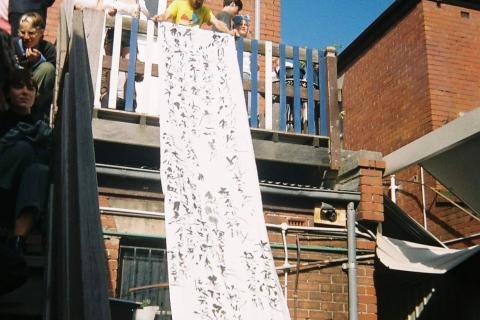 The heart sutra written in black calligraphy on a long white banner at the Narrm launch of HER 他 in 2020, shortly before the first COVID lockdown.