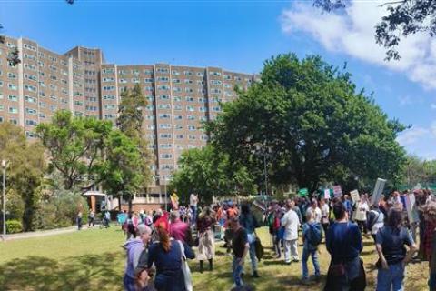 A wide shot of public housing towers at the Flemington estate and a crowd of people at the rally to save public housing.