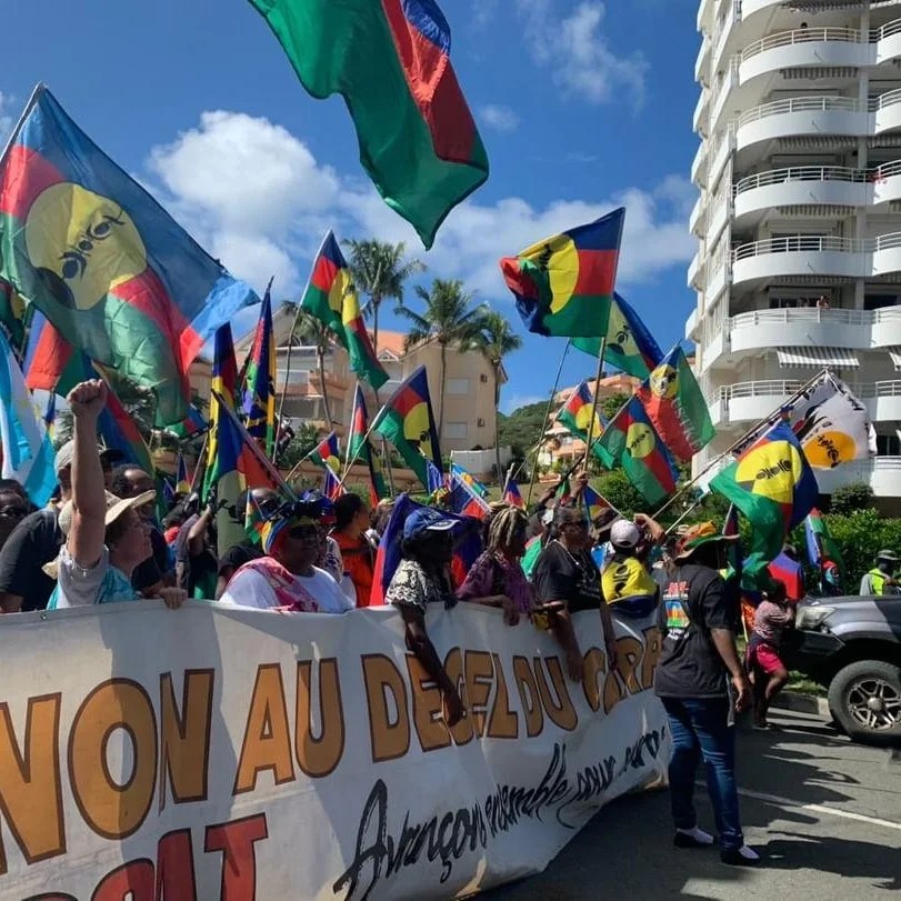 Pro-independence protesters in Kanaky with banner, Kanaky flags