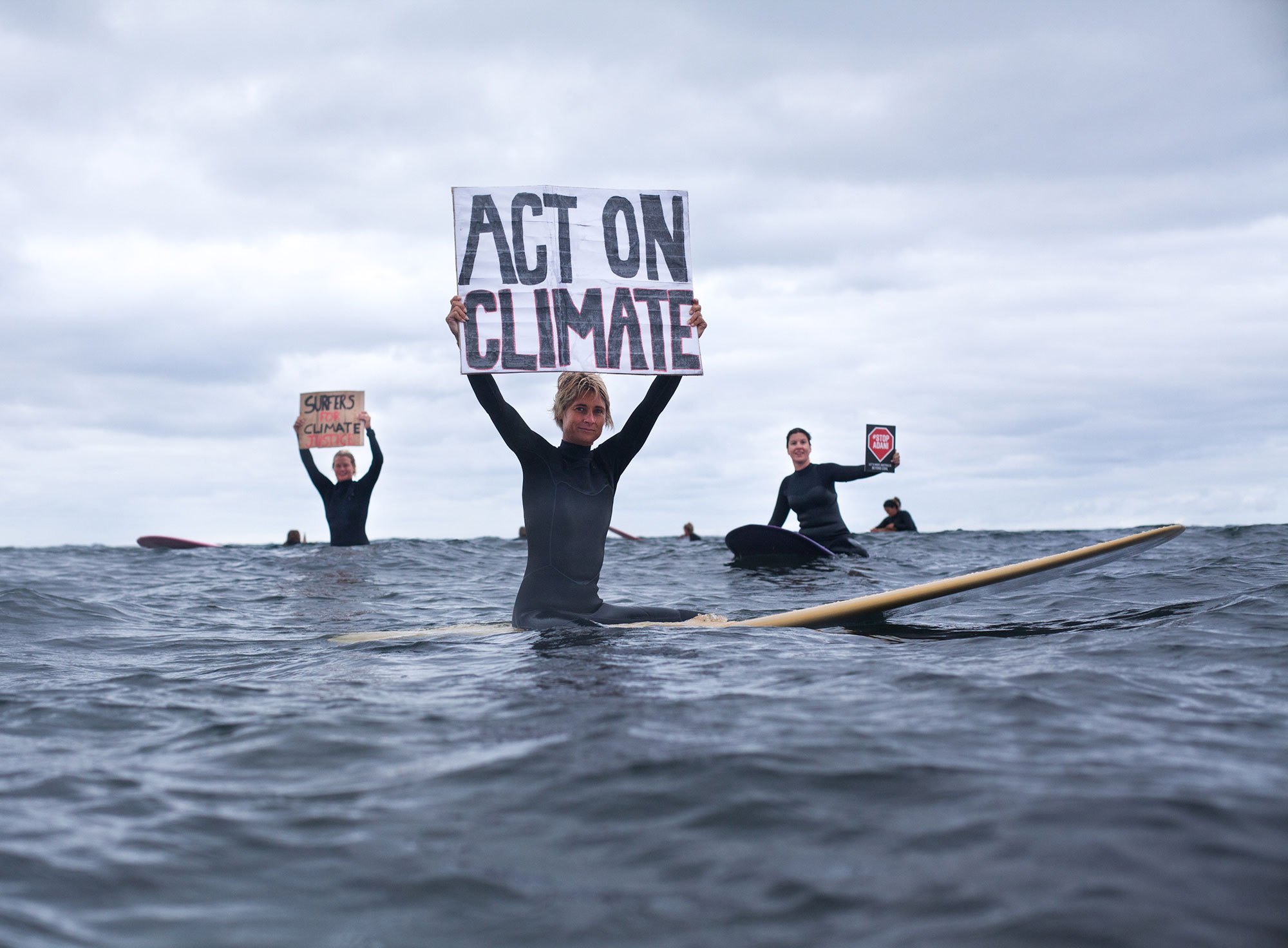 Surfers with an Act on Climate sign