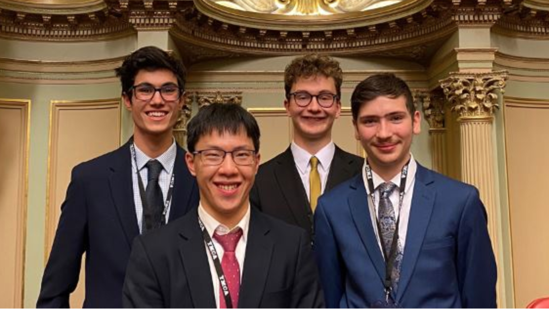 4 high school students in uniform smiling in parliament house