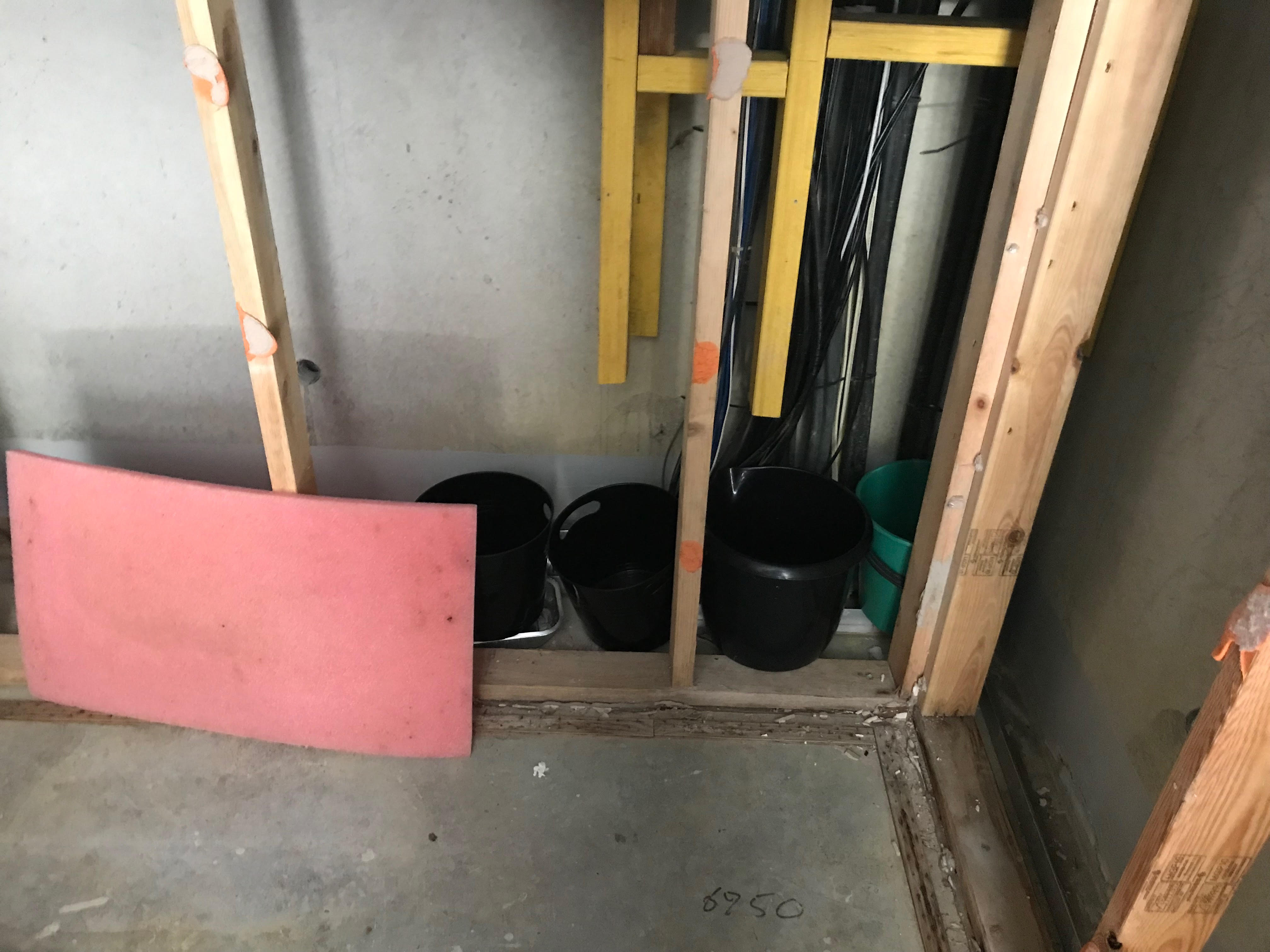 A row of buckets lined up inside the wall of a retirement village unit to catch rainwater