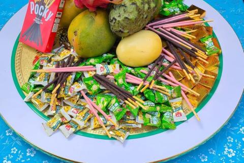 A large plate offering pocky biscuits, mango, dragon fruit, soursop and lollies 