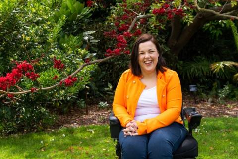 Peta Hooke has Cerebral Palsy and is sitting in a garden in her electric wheelchair.