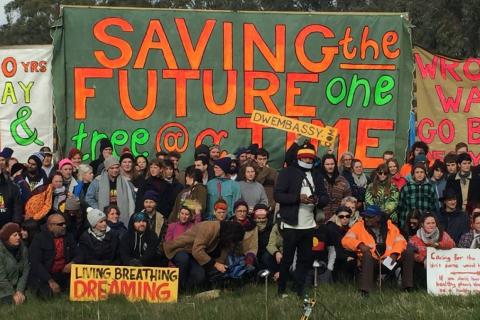 Crew gathered outside Embassy with protest banners saying saving the future one tree at a time, and other similar slogans & Aboriginal flag