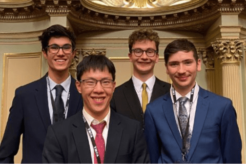 4 high school students in uniform smiling in parliament house