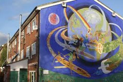 A large house with a mural painted on the side depicting the earth with a group of people riding around it on rockets