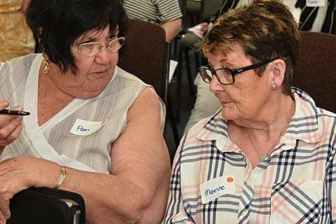 Two dark haired women sit side by side