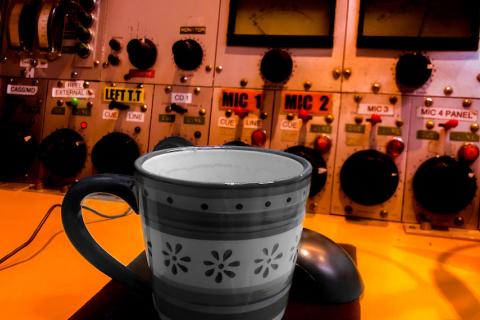 A cup in the foreground of 3CR studio panel